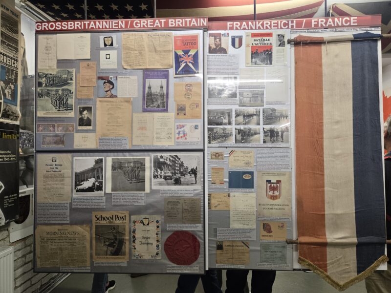 Exhibit board with British and French historical documents, flags, and posters in a museum display.